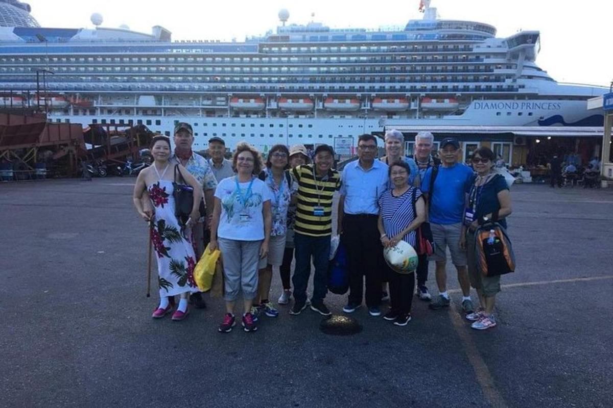 um grupo de pessoas em pé em frente a um navio de cruzeiro