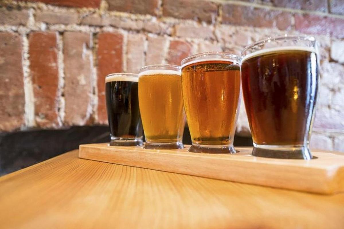 four glasses of beer sitting on a wooden tray