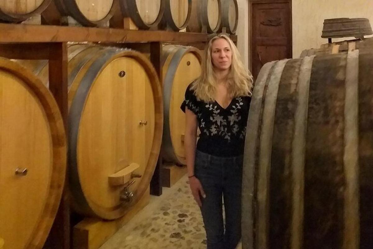ženska, ki stoji poleg kupa vinskih sodov