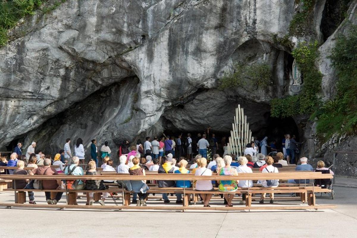 a group of people sitting on a bench in front of a cave