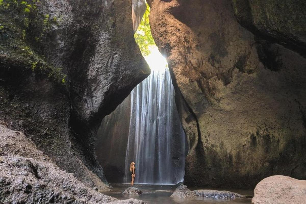 una persona in piedi di fronte a una cascata in una grotta
