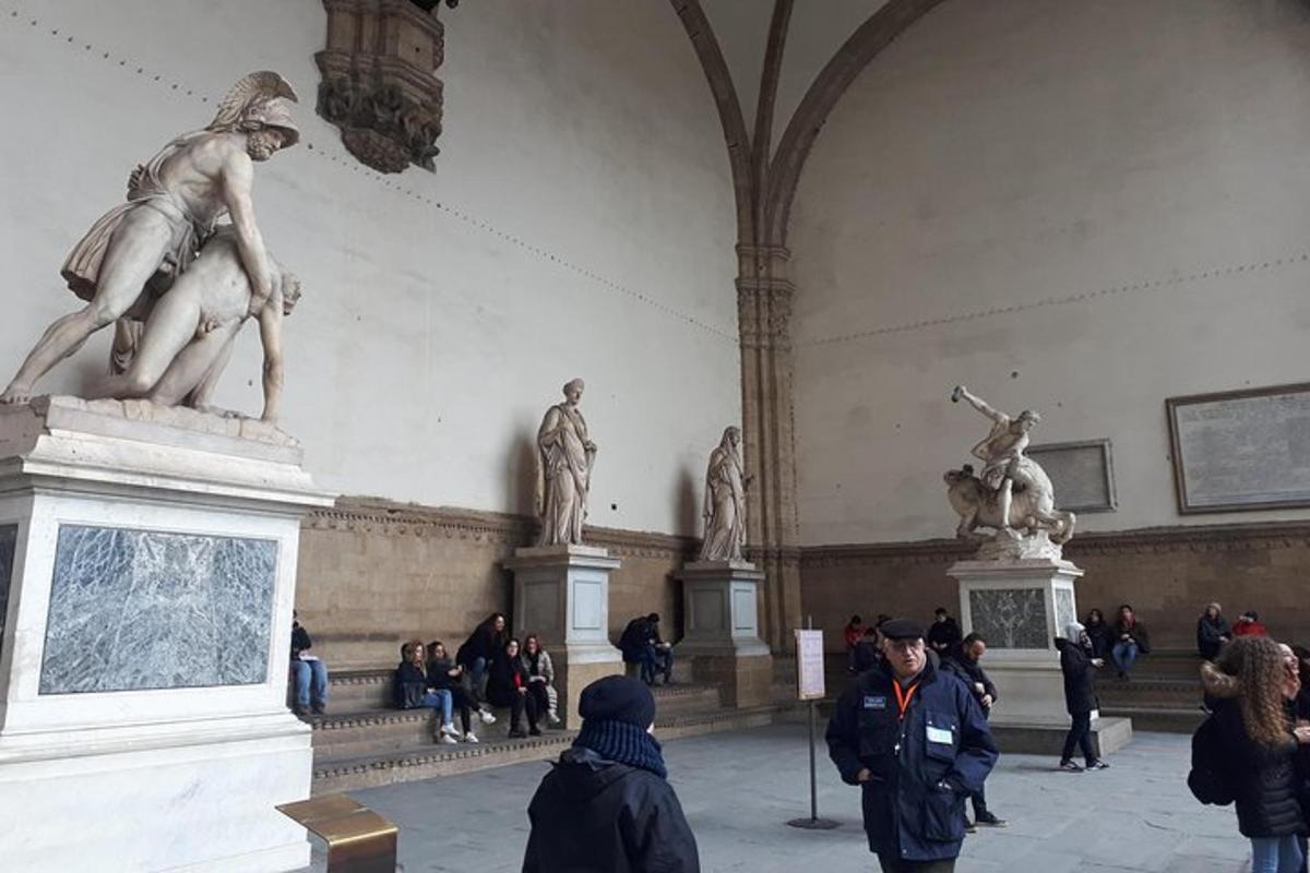 a group of people walking around a museum with statues