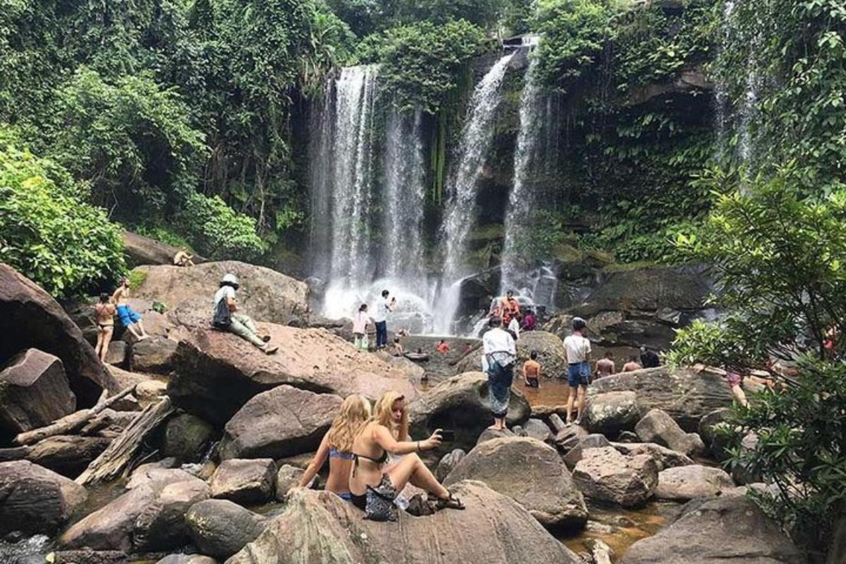 un gruppo di persone sedute sulle rocce di fronte a una cascata