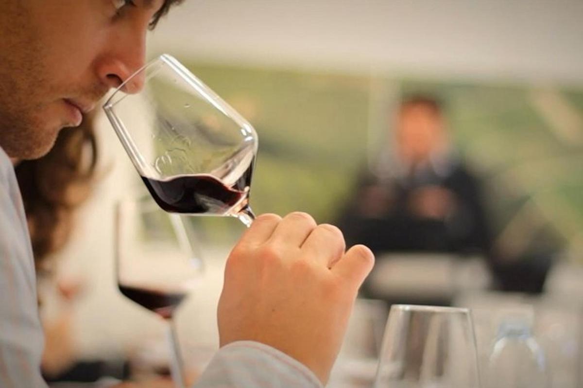 a man drinking a glass of red wine