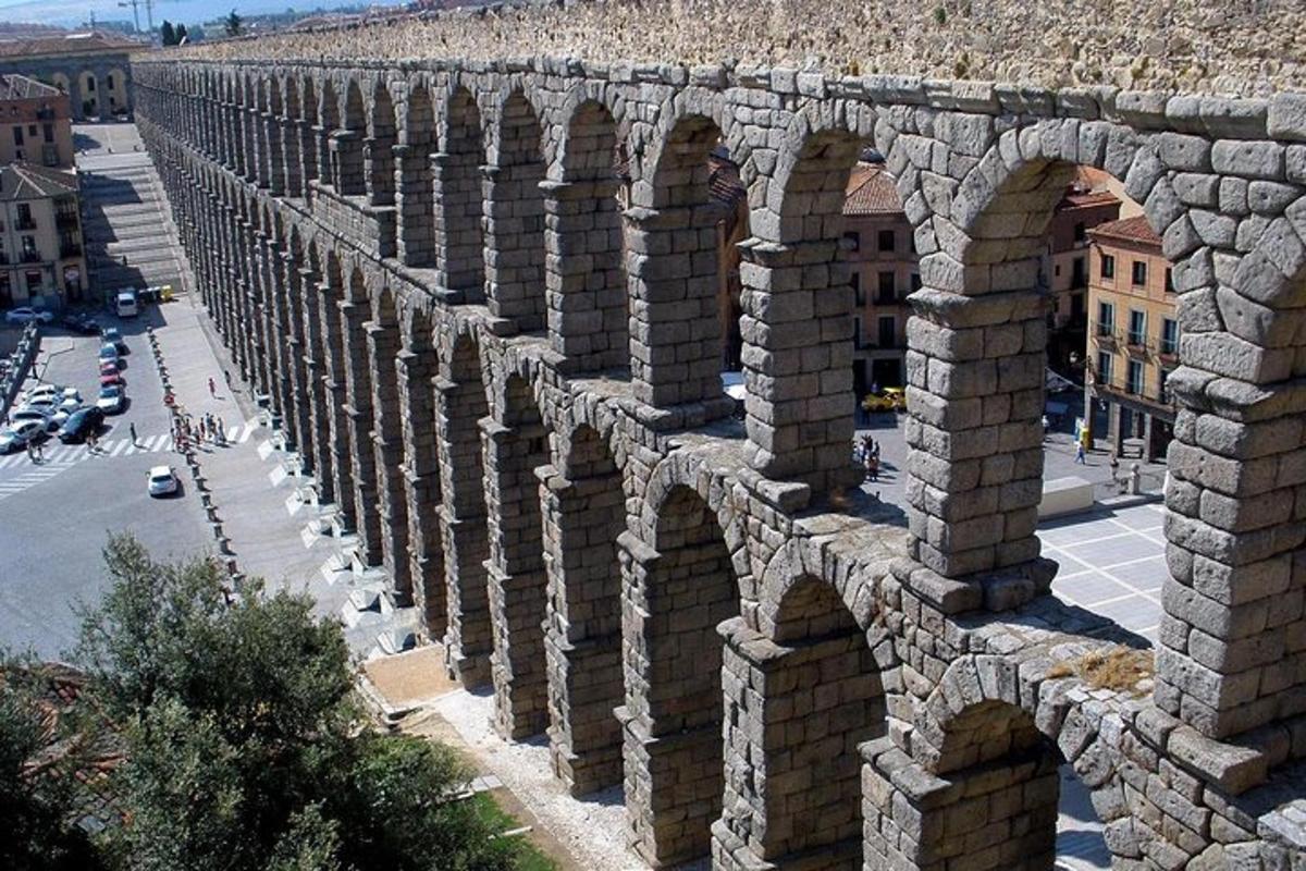 un vecchio muro di pietra con archi su una strada cittadina