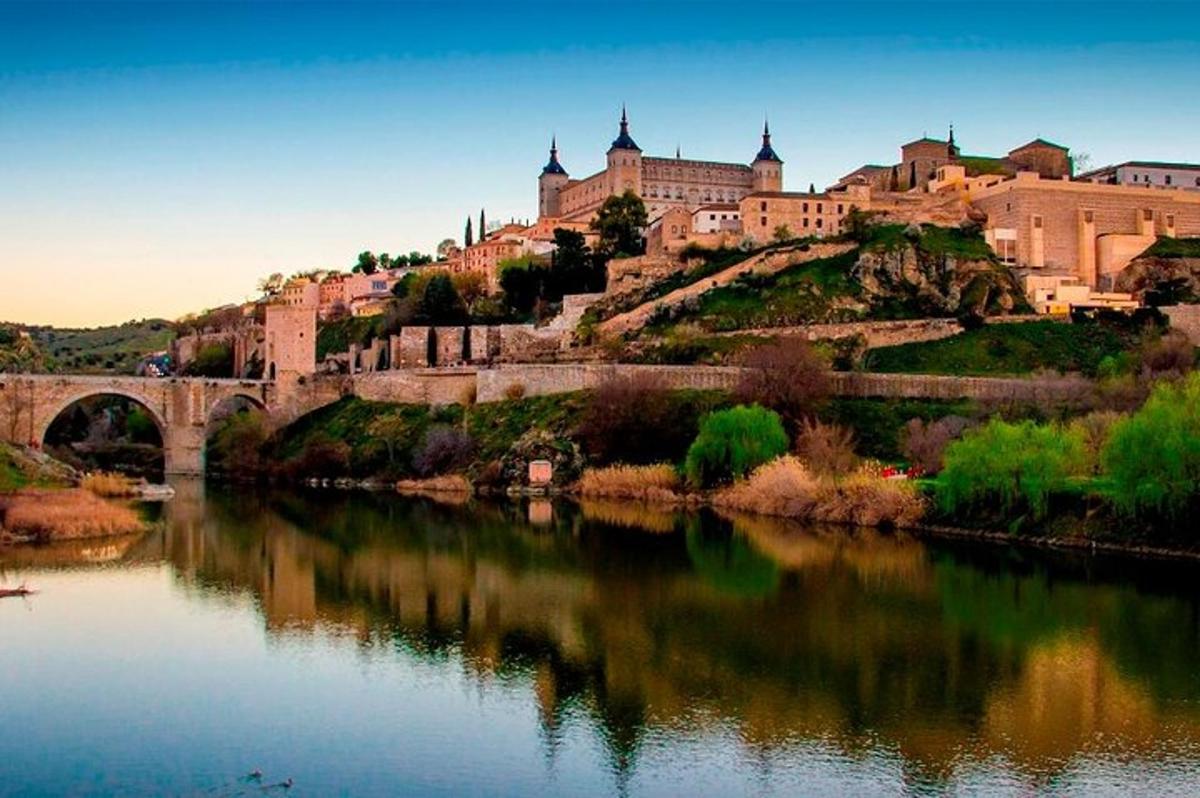 a castle on a hill next to a river with a bridge