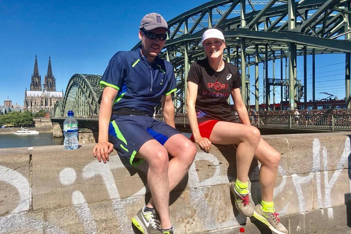 um homem e uma mulher sentados em um muro em frente a uma ponte