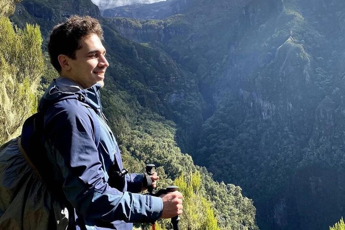 čovjek stoji na vrhu planine i drži kameru
