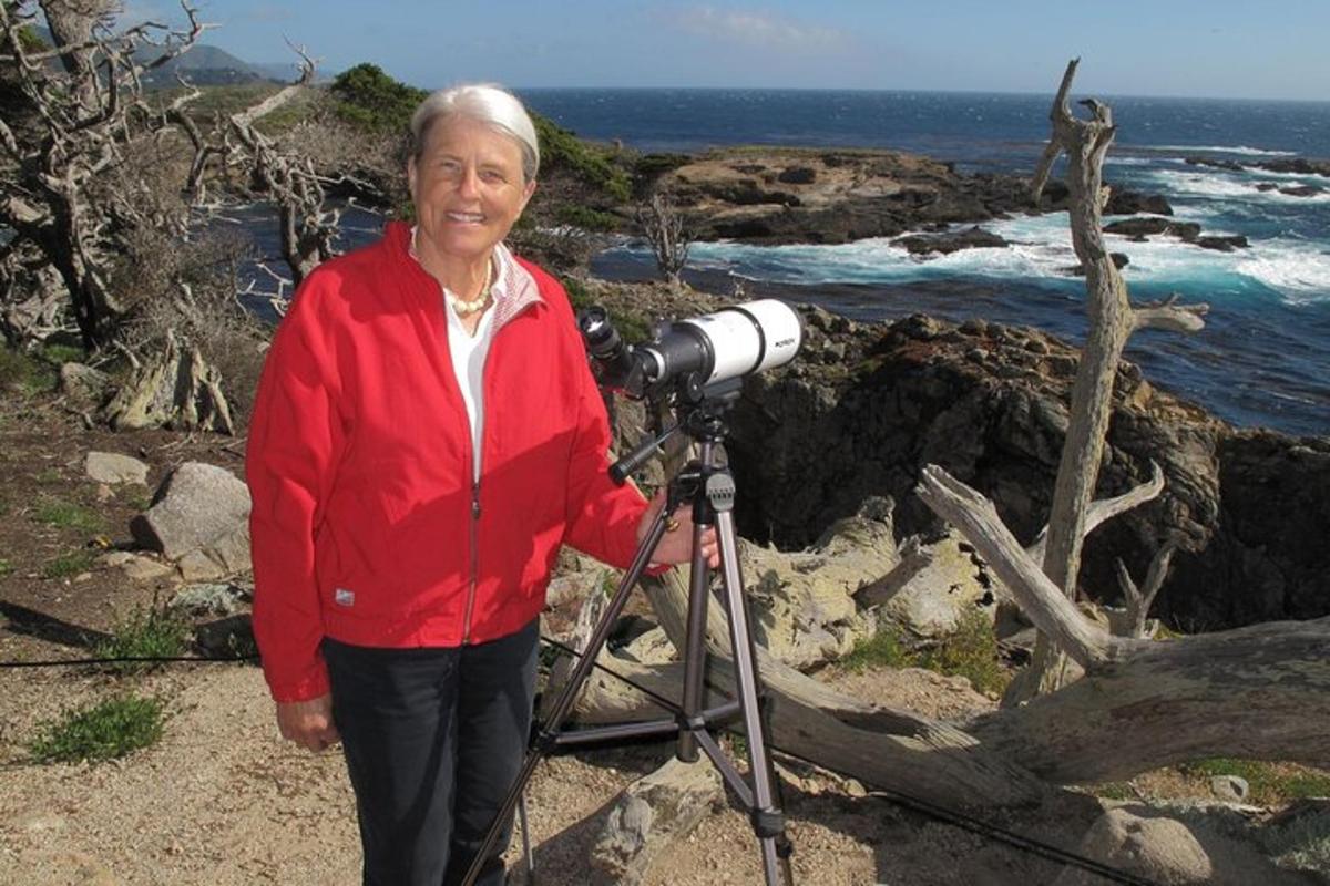 a woman standing next to a camera on the beach