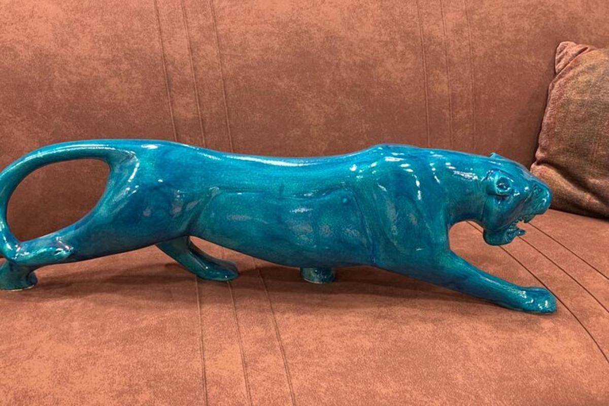 en blå glasløvestatue siddende på en sofa