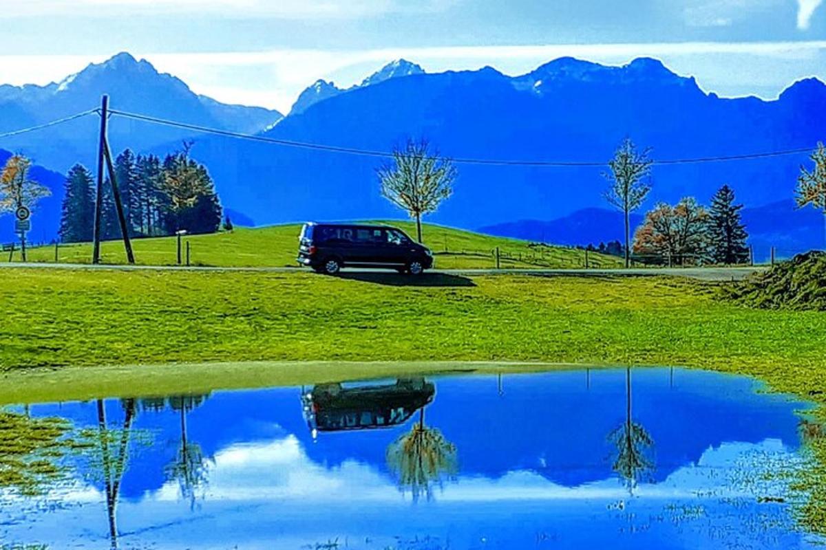 un'auto parcheggiata in un campo con un riflesso in uno stagno