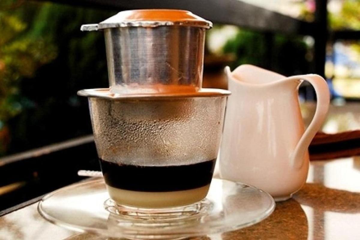 una tazza di caffè appoggiata su un tavolo accanto a una brocca