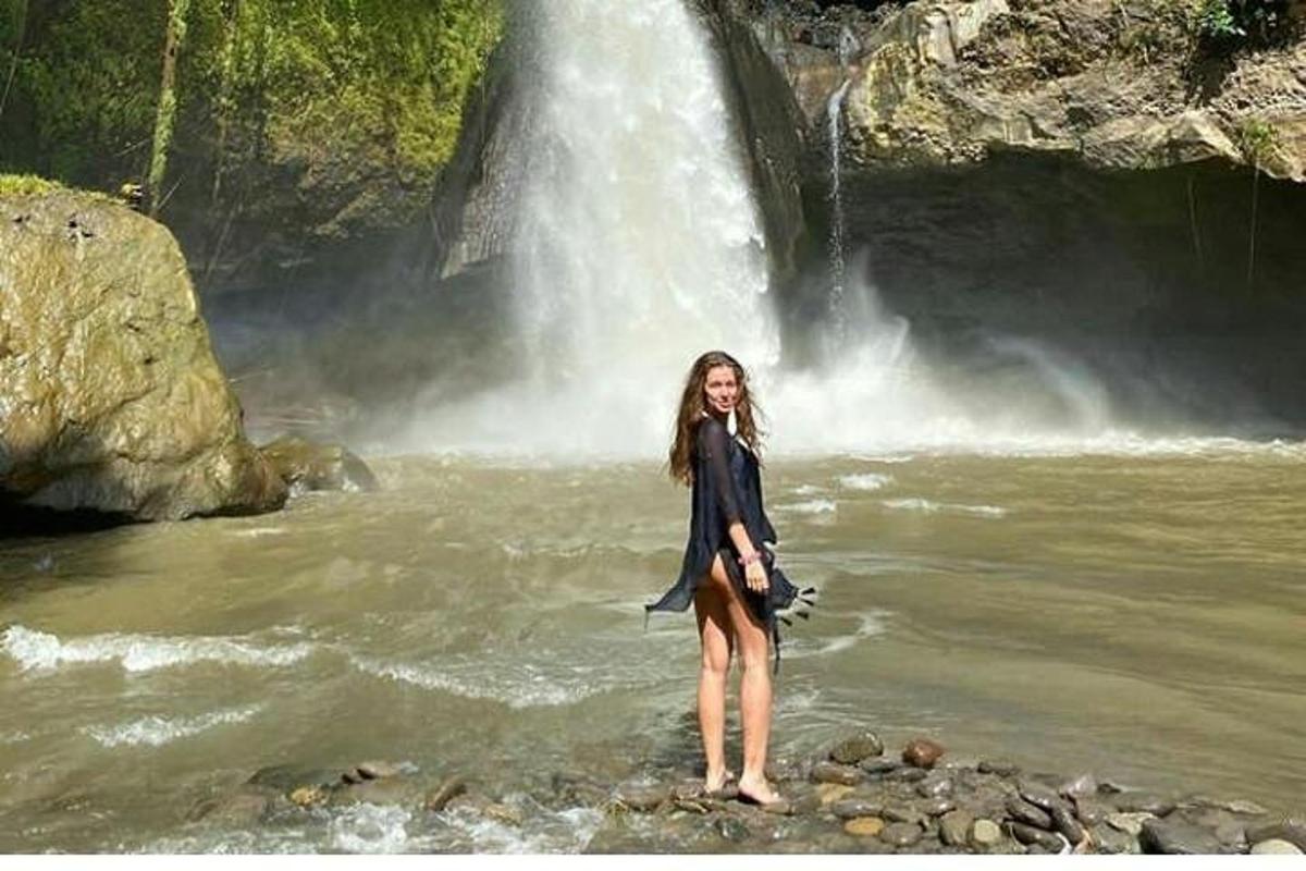 жена стоји у води испред водопада