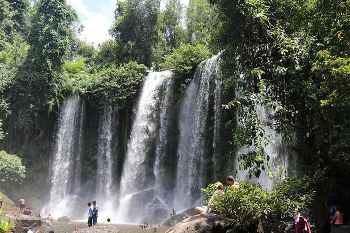 Un grupo de personas de pie frente a una cascada.
