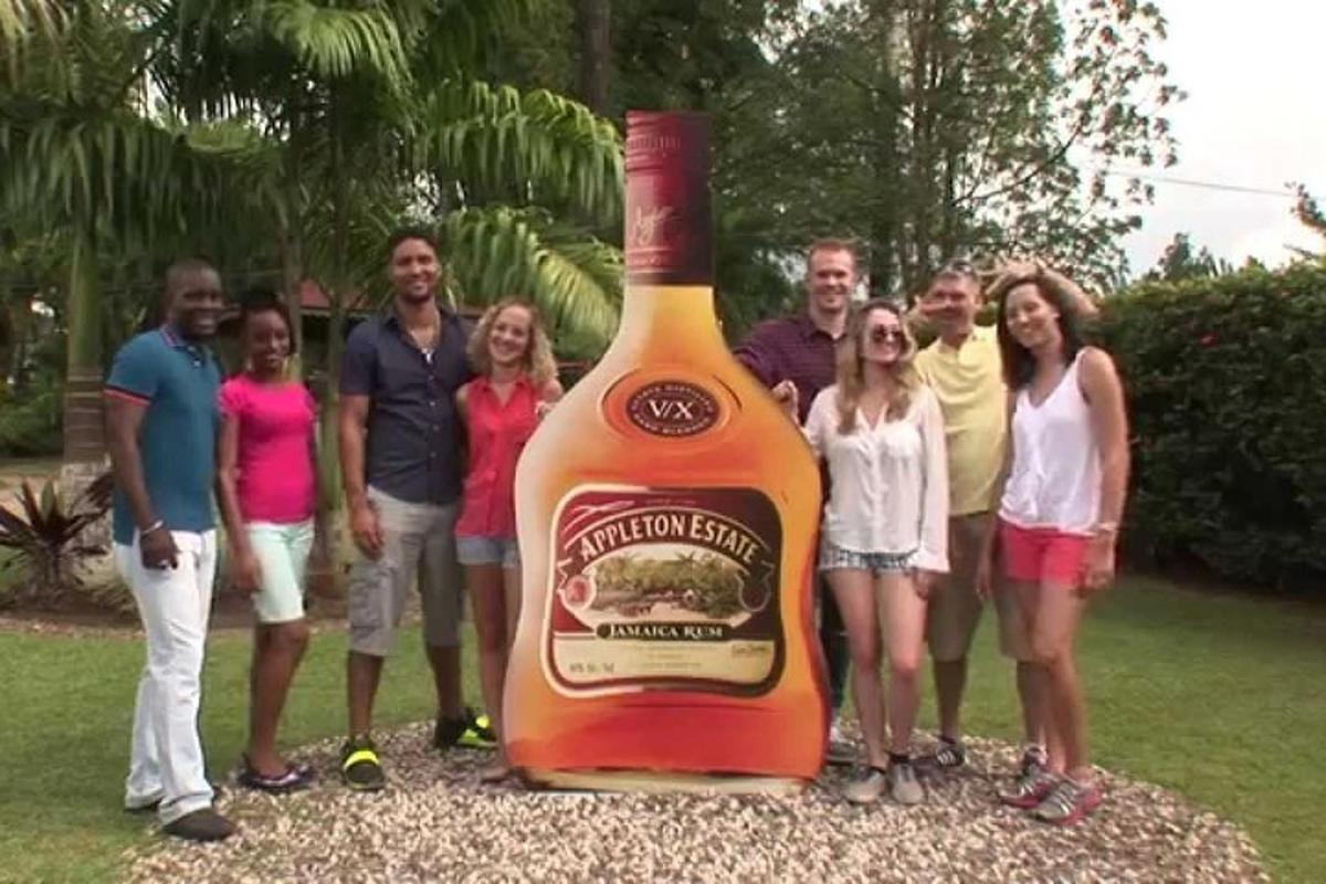 skupina ľudí stojacich vedľa veľkej fľaše alkoholu