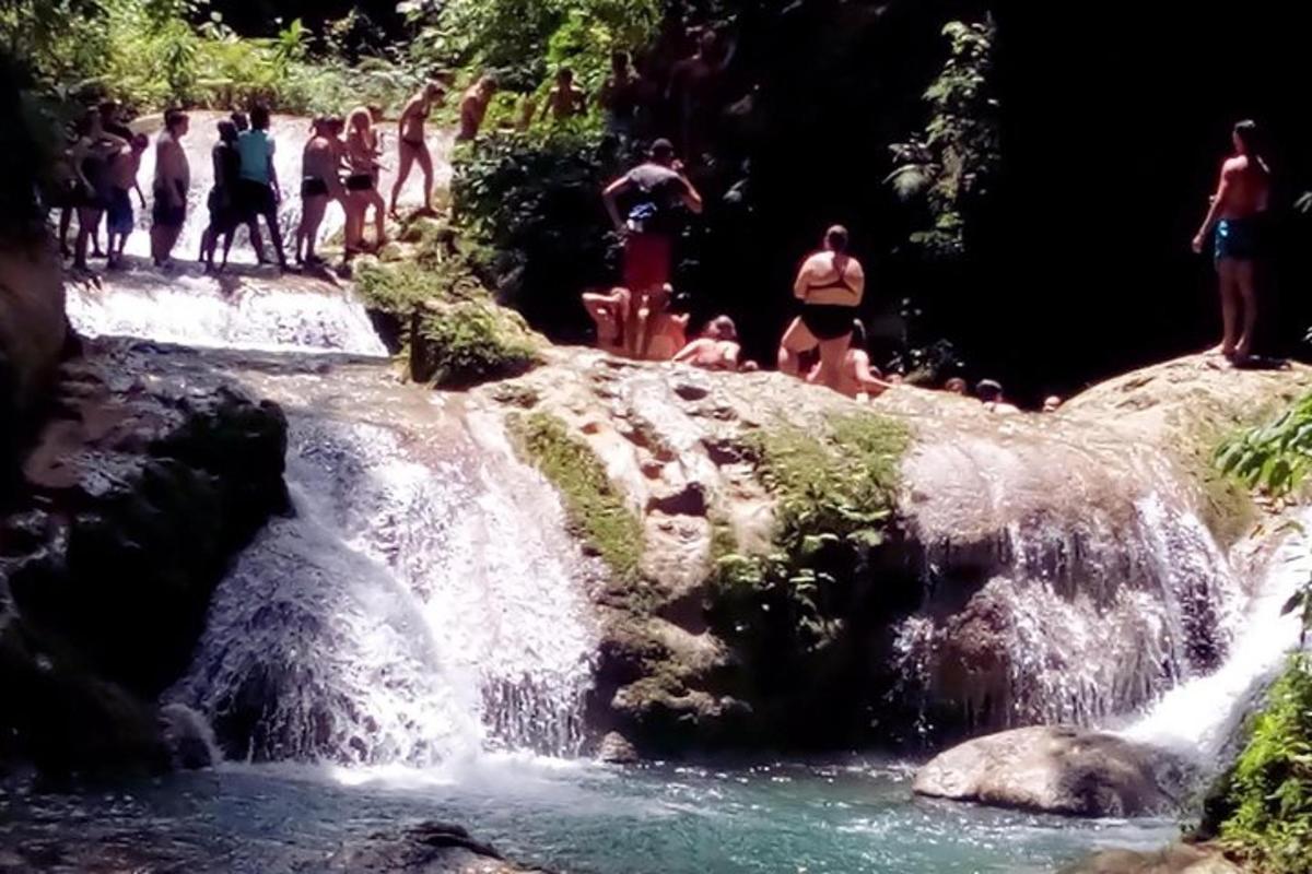 група људи у купаћим костимима стоји у водопаду