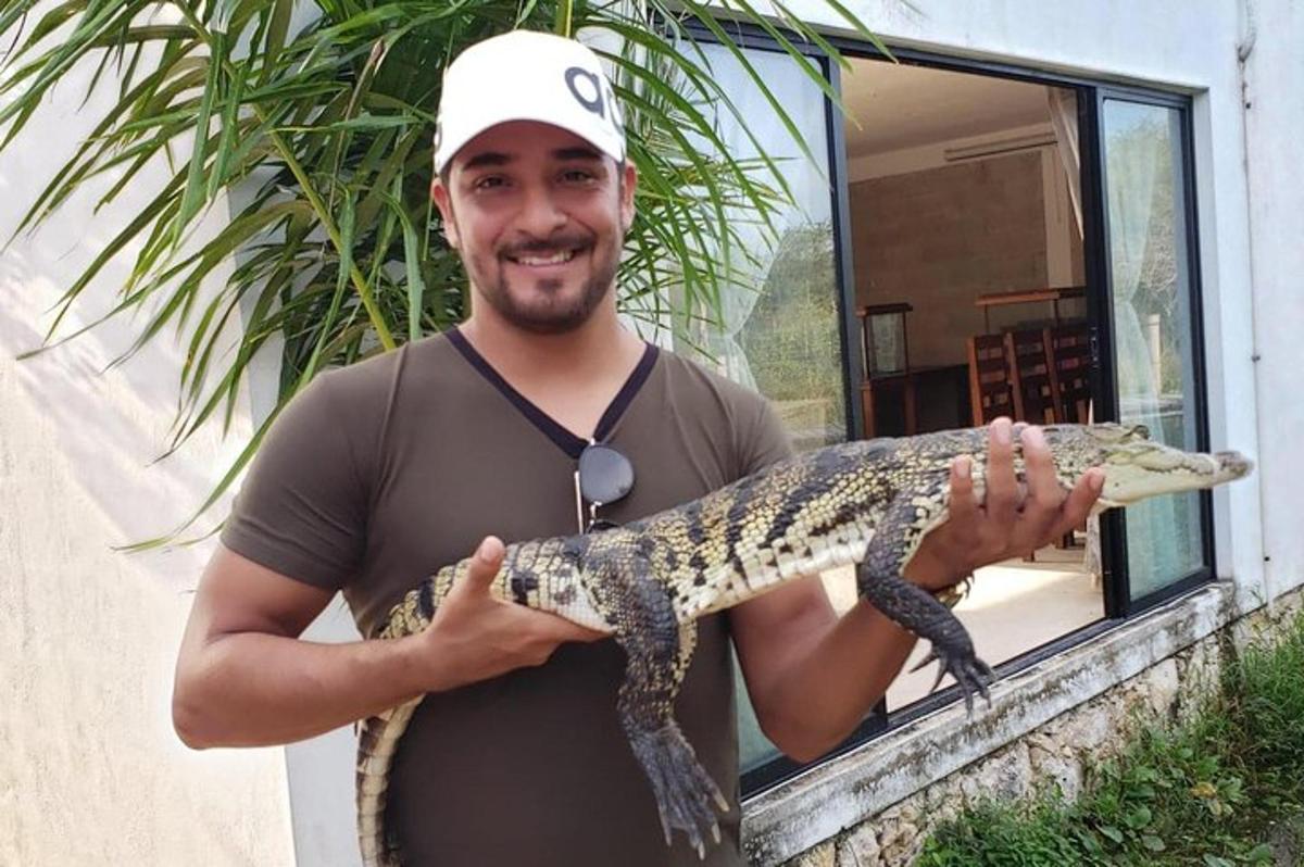muž drží velkého aligátora