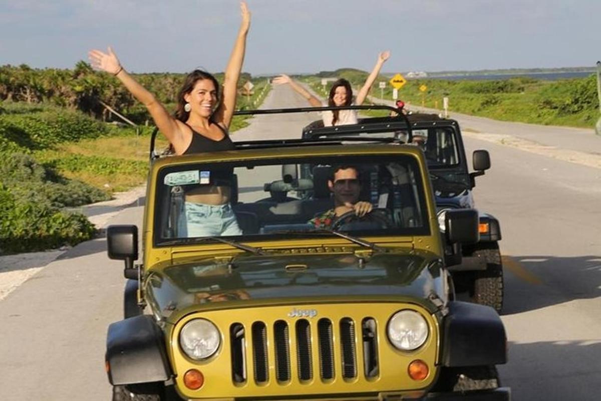 două persoane într-un jeep cu brațele în aer