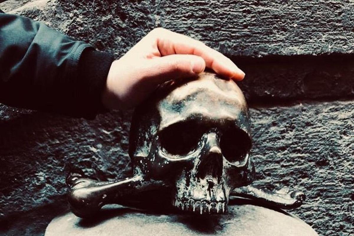 una persona sosteniendo una calavera en el suelo