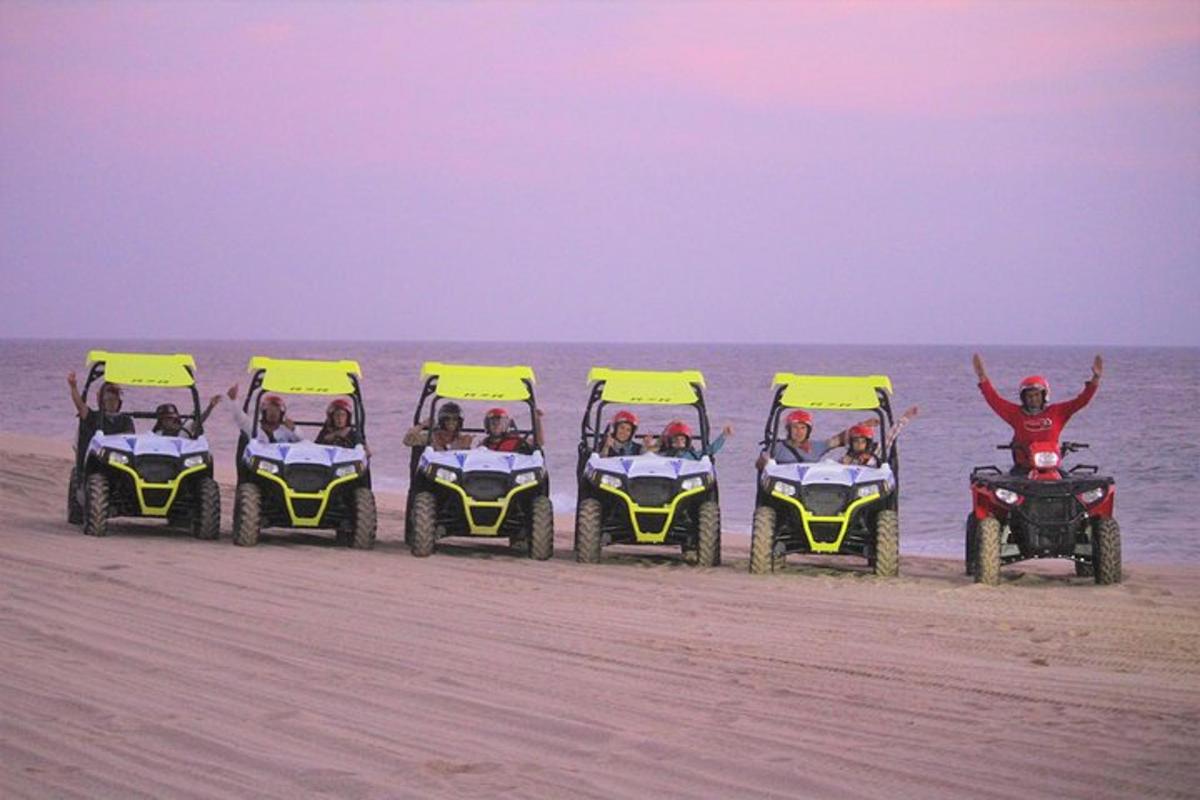 een groep mensen die in vier vierwielers op het strand rijden