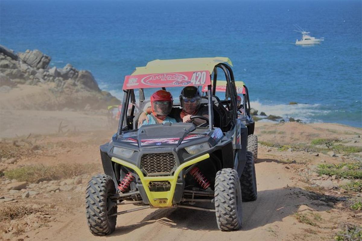 două persoane într-un jeep pe un drum de pământ