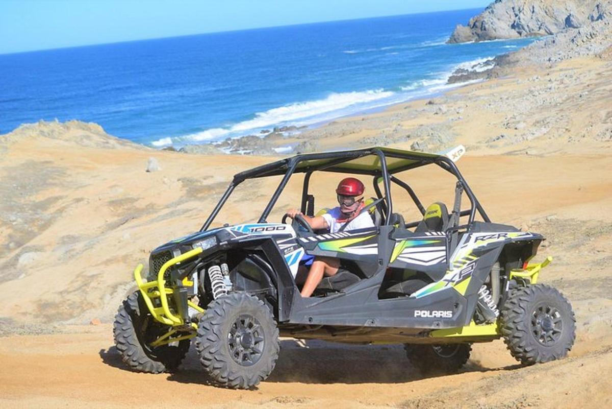 un bărbat stând într-un ATV pe plajă