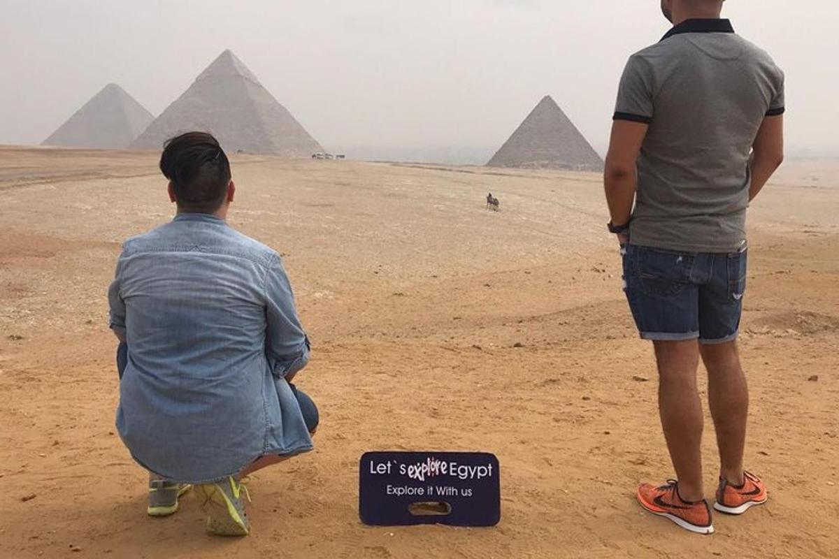 dua pria duduk di padang pasir sambil memandangi piramida