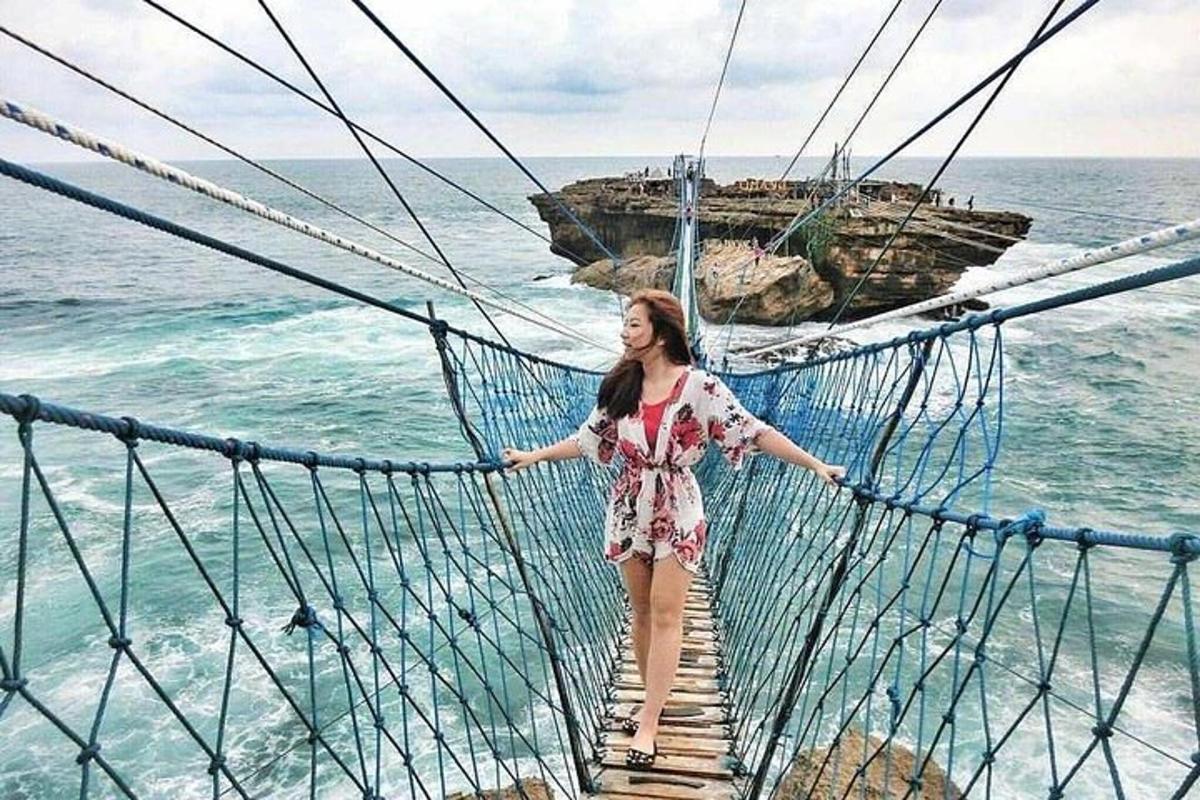 una donna in piedi su un ponte sospeso sopra l'oceano