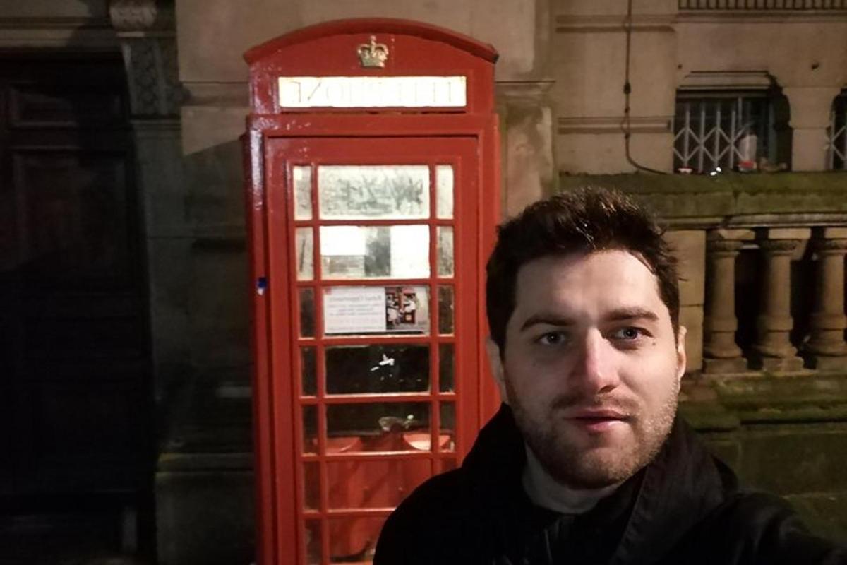 a man sitting in front of a red phone booth