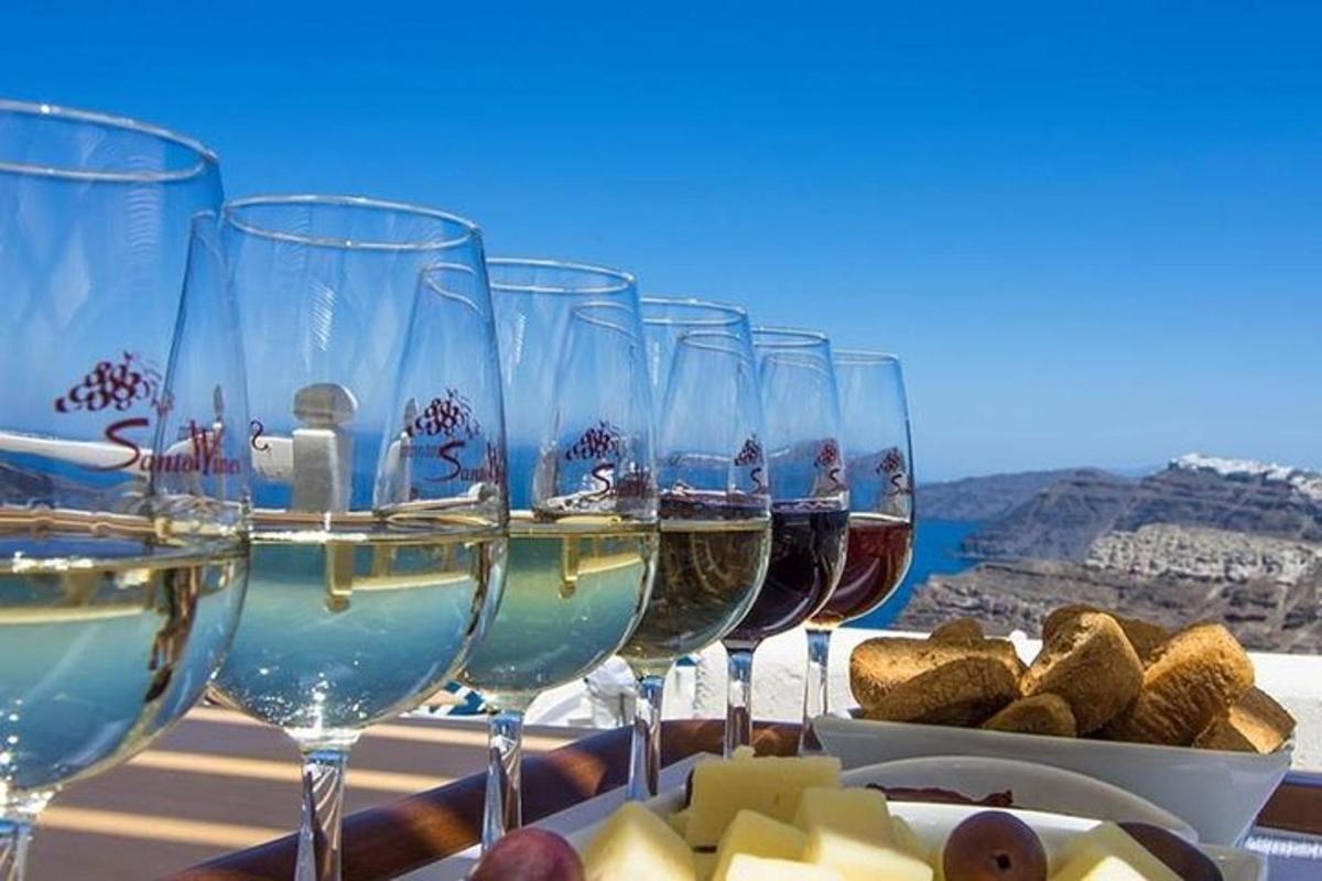 un rând de pahare de vin așezate pe o masă cu brânză și struguri