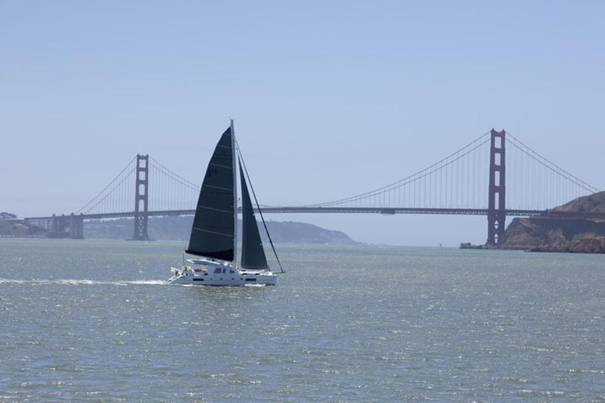 a sailboat in the water with a bridge in the background