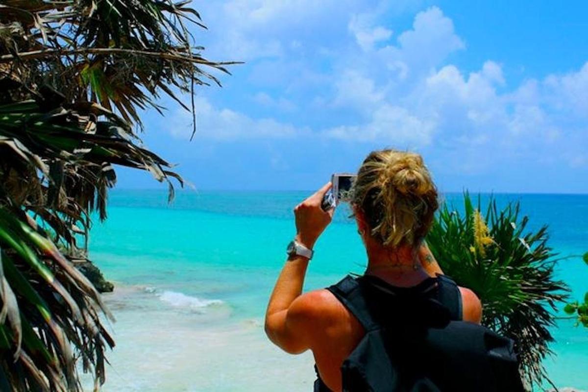 seorang wanita mengambil gambar laut dengan ponselnya