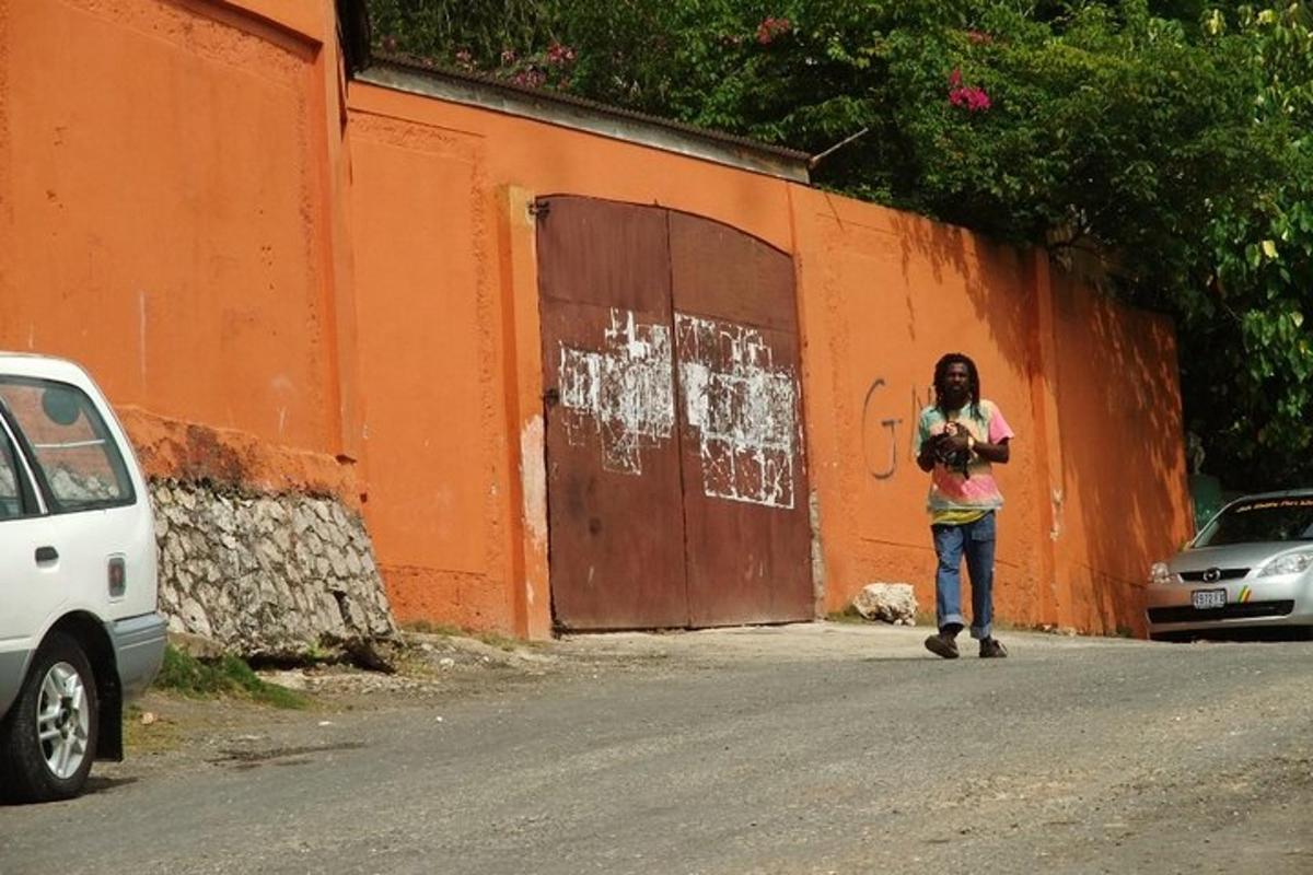 seorang wanita berjalan di jalan di sebelah dinding oren