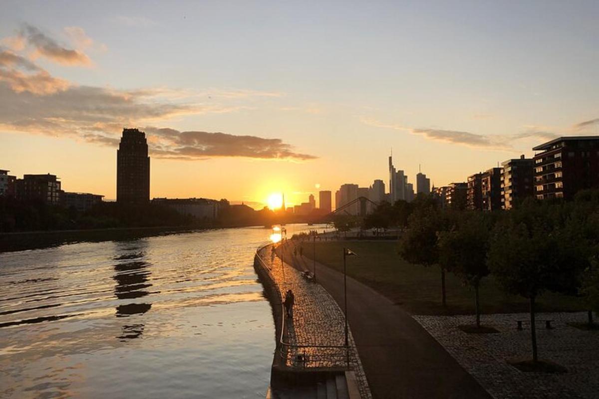 a sunset over a river with a city in the background