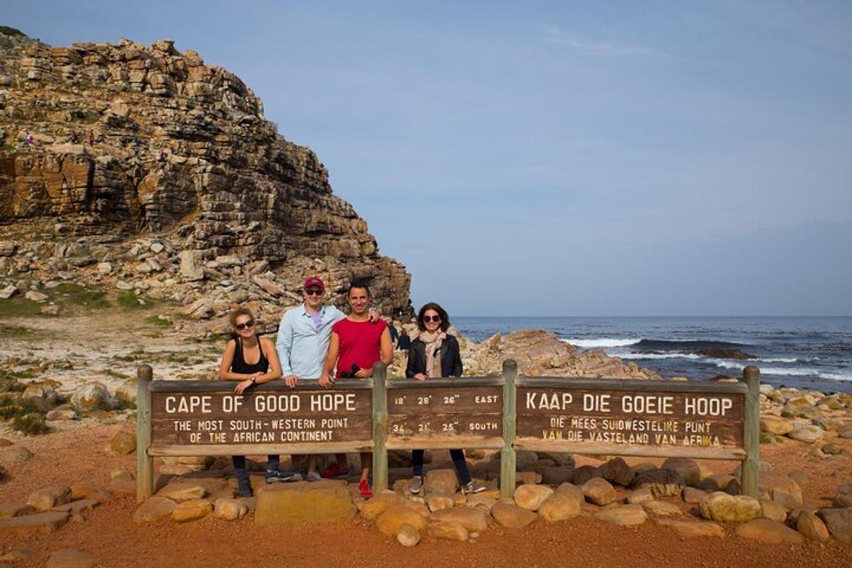 a group of people standing on a sign at the beach