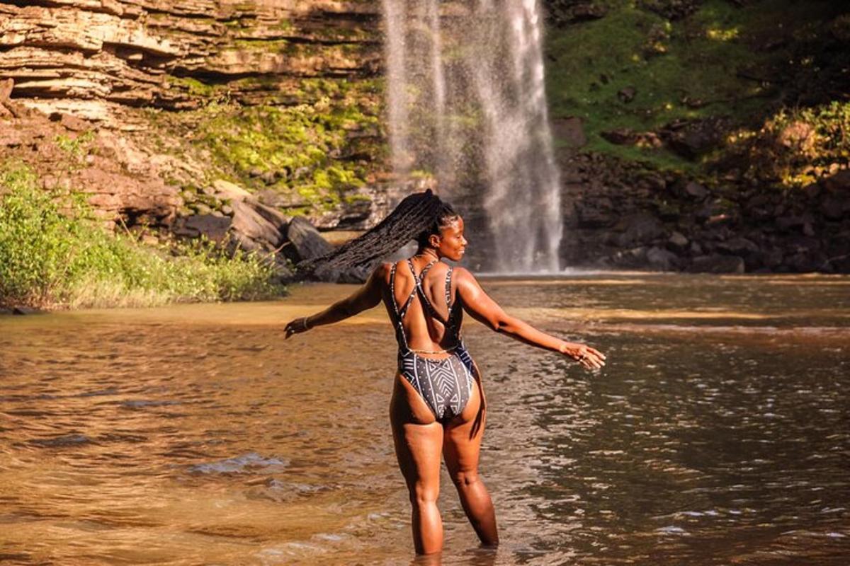 a woman standing in the water in front of a waterfall