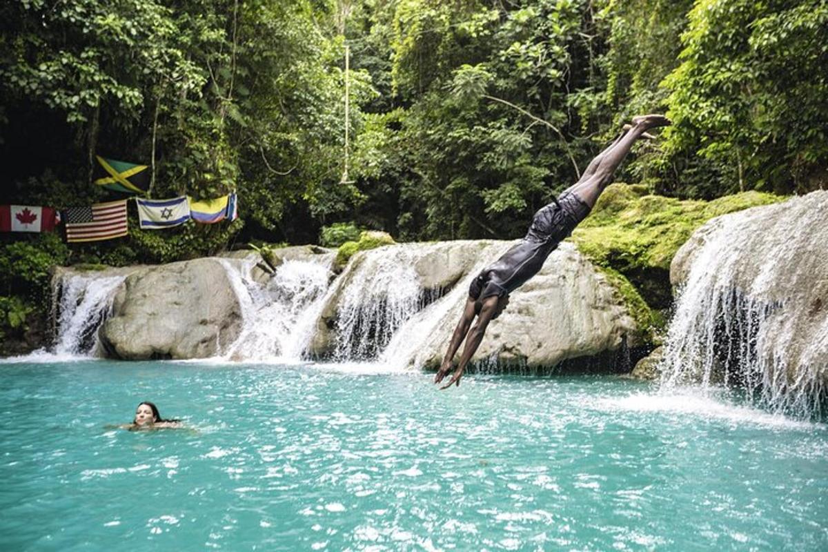 una persona che si tuffa in una piscina di fronte a una cascata