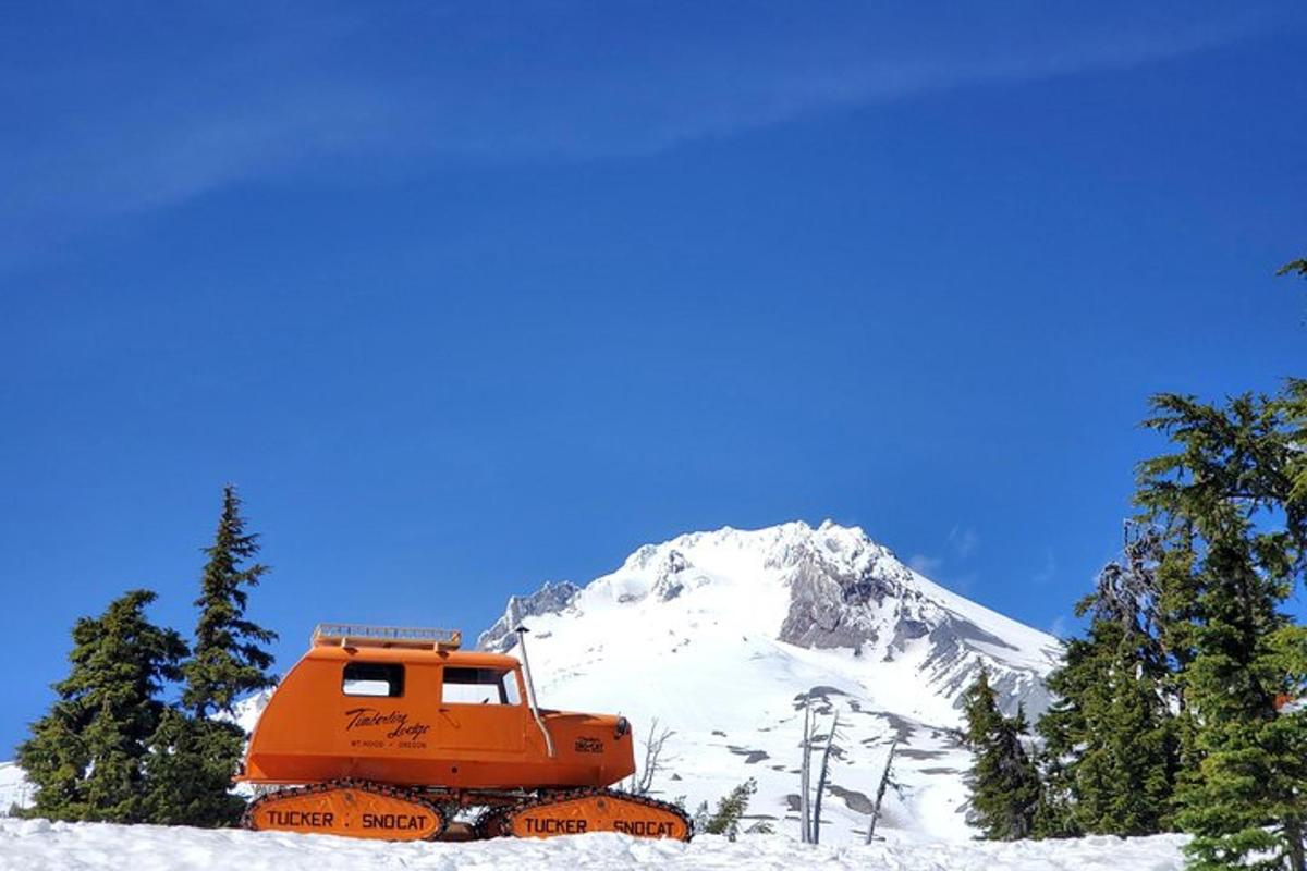 an orange truck in front of a snow covered mountain