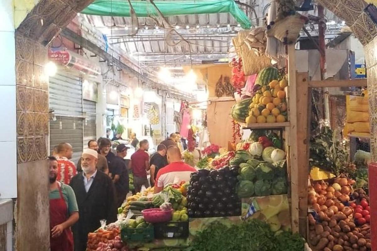 un grup de persones passejant per un mercat amb fruites i verdures
