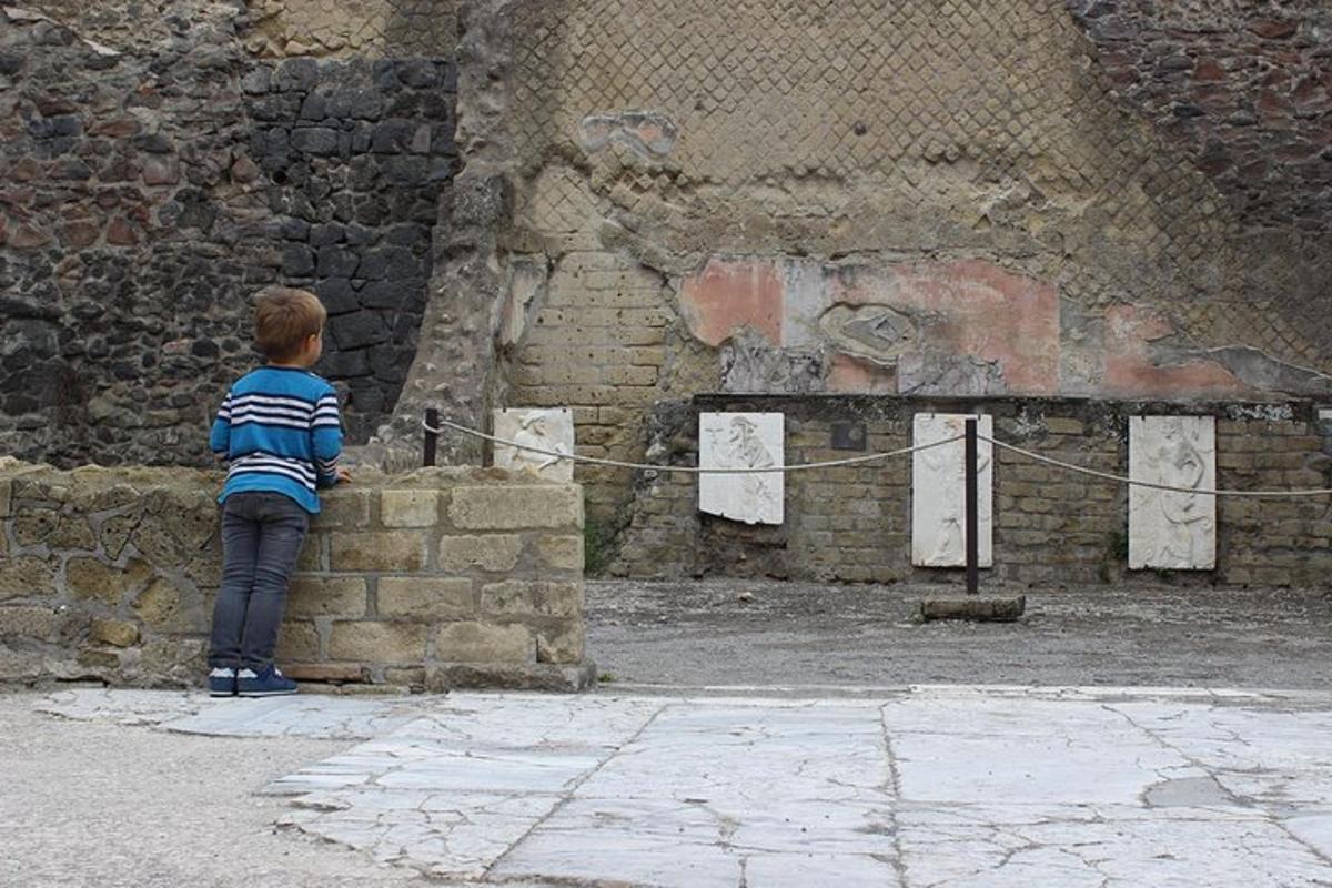 ένα μικρό αγόρι στέκεται σε έναν τοίχο