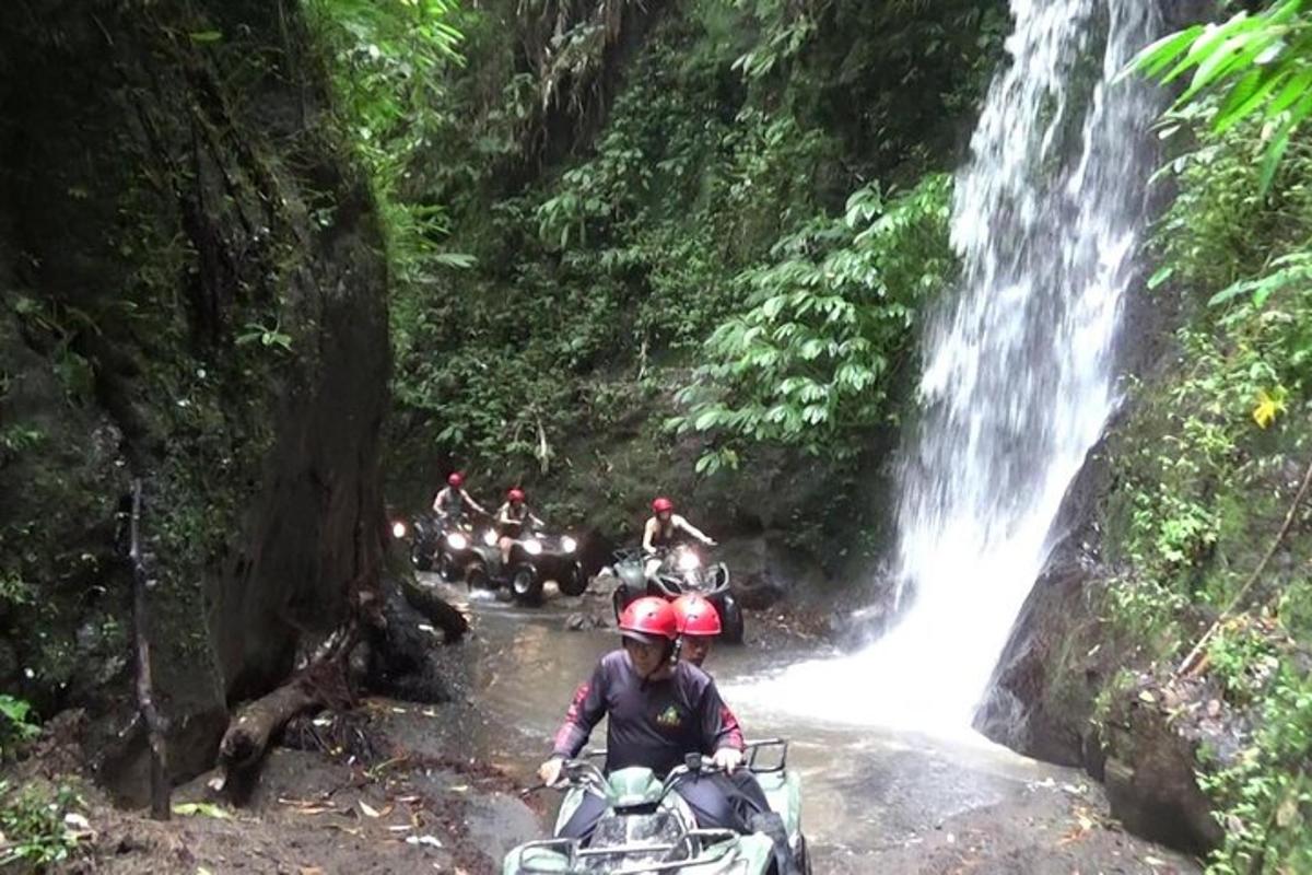 eine Gruppe von Menschen, die mit Motorrädern durch einen Wasserfall fahren