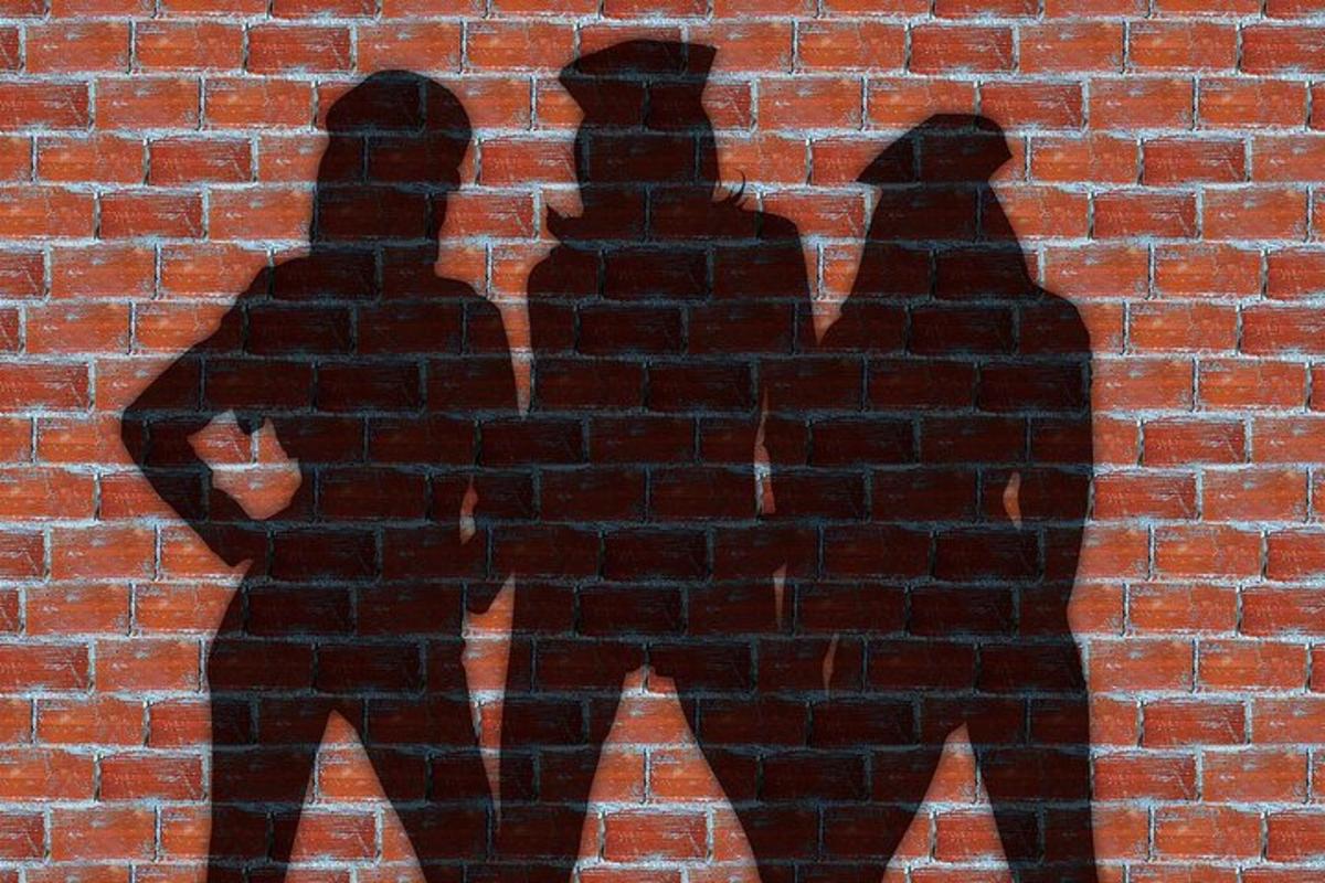 una ombra de tres persones en una paret de maons