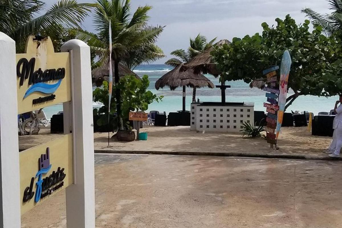 a sign in front of a beach with a surfboard