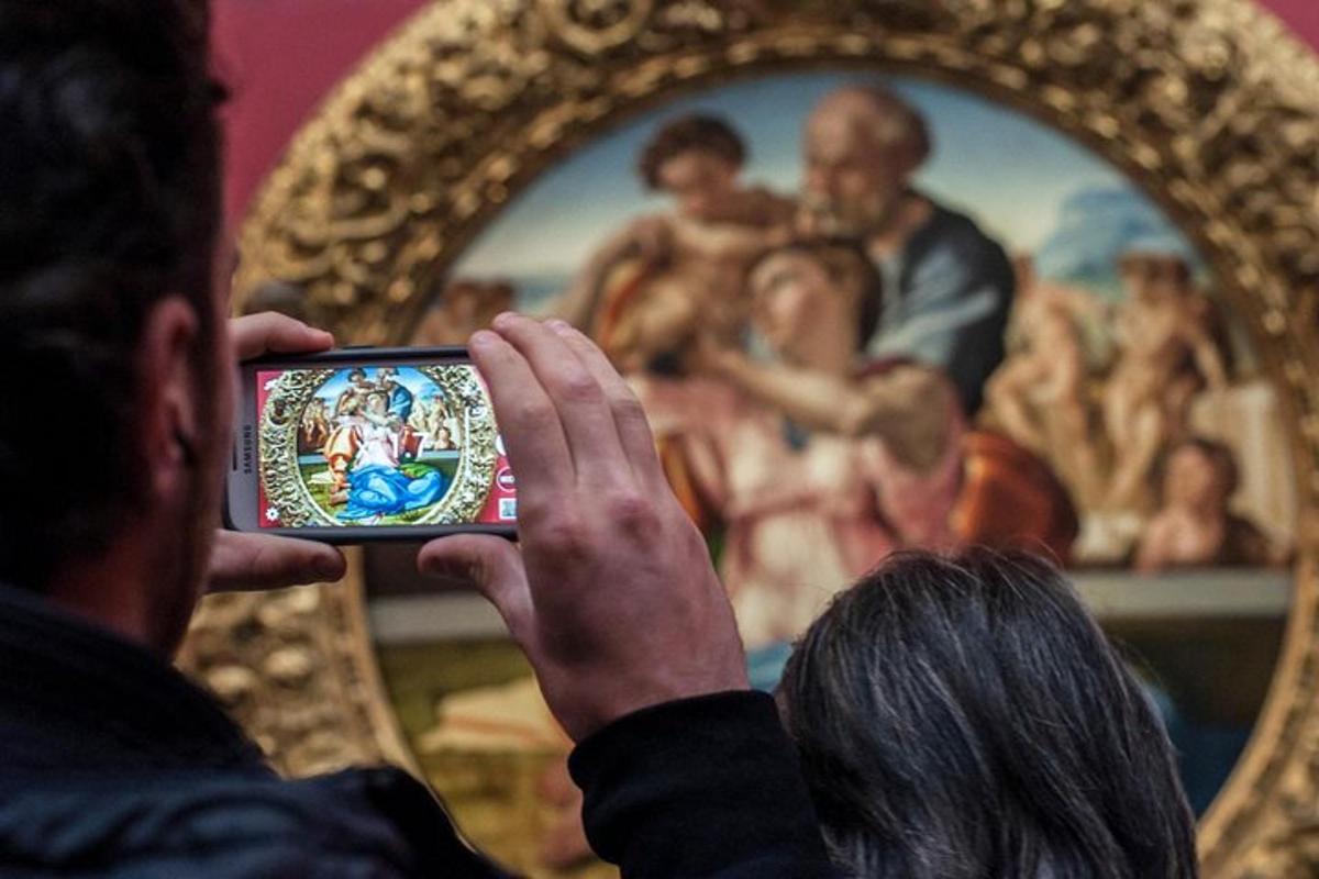 Un hombre tomando una foto de un cuadro con su teléfono móvil.