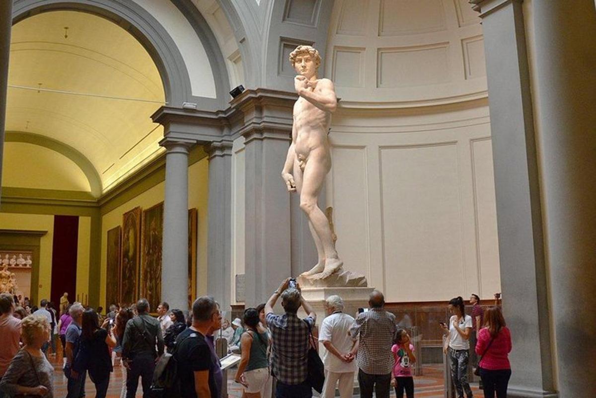 una folla di persone che guarda una statua in un museo