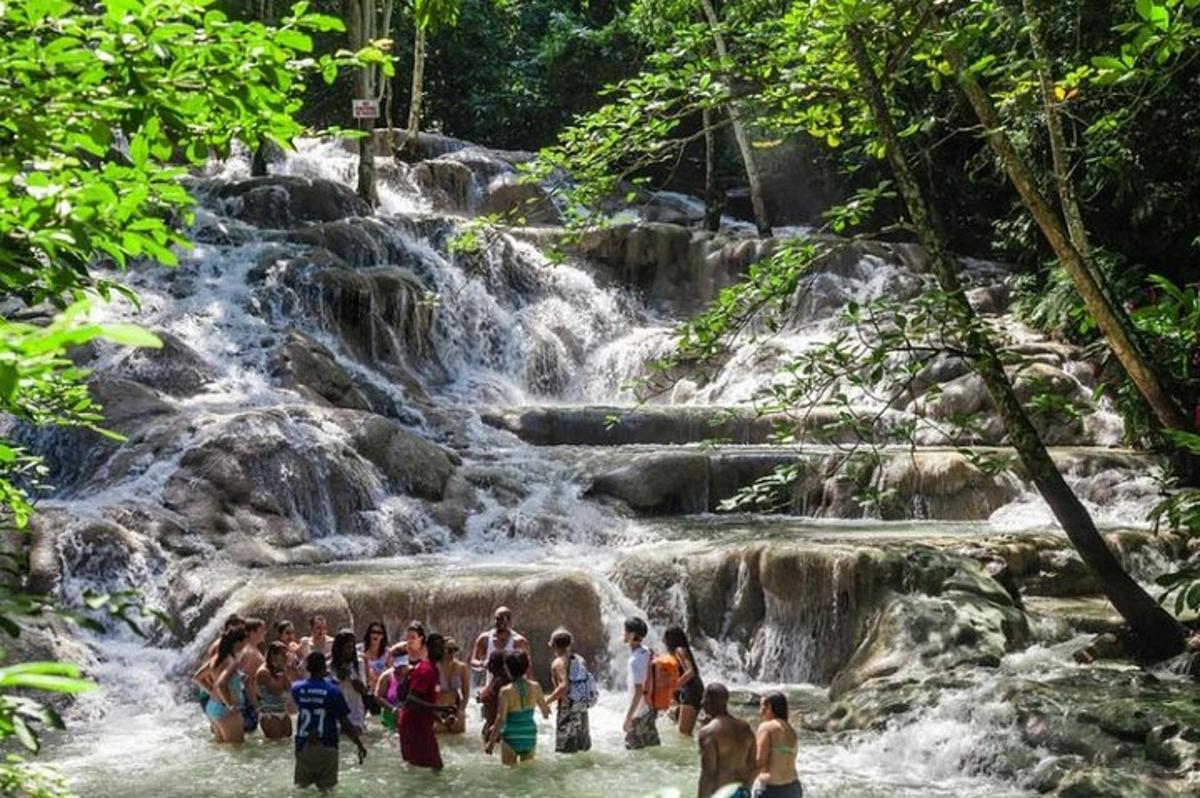 um grupo de pessoas na água em frente a uma cachoeira