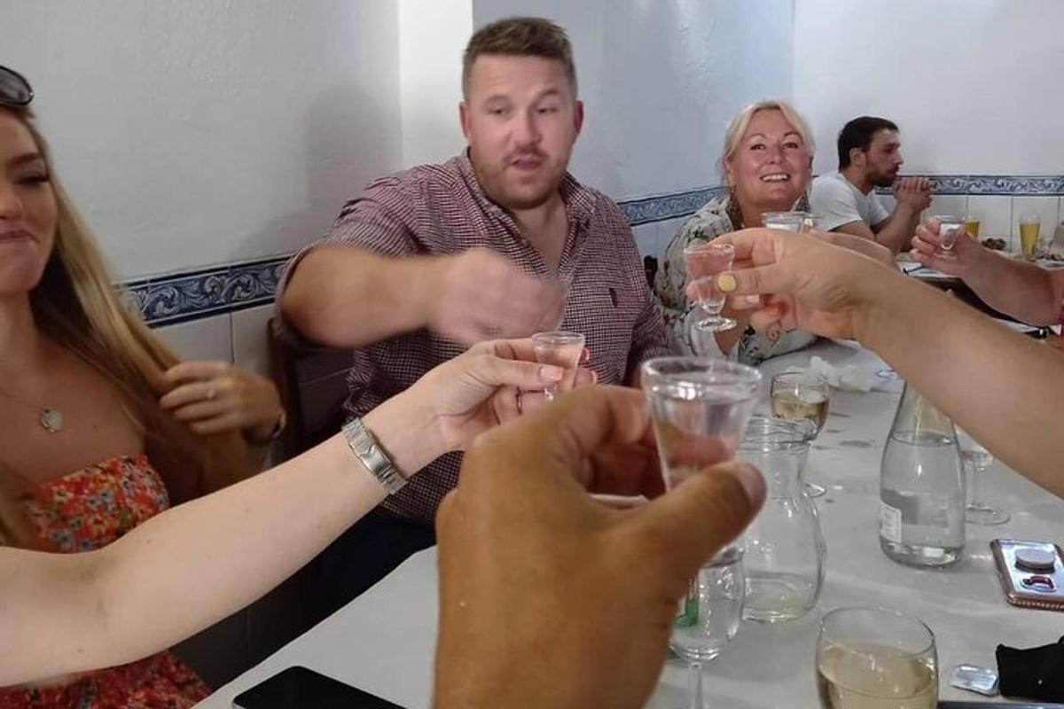 Un grupo de personas sentadas alrededor de una mesa bebiendo vino.