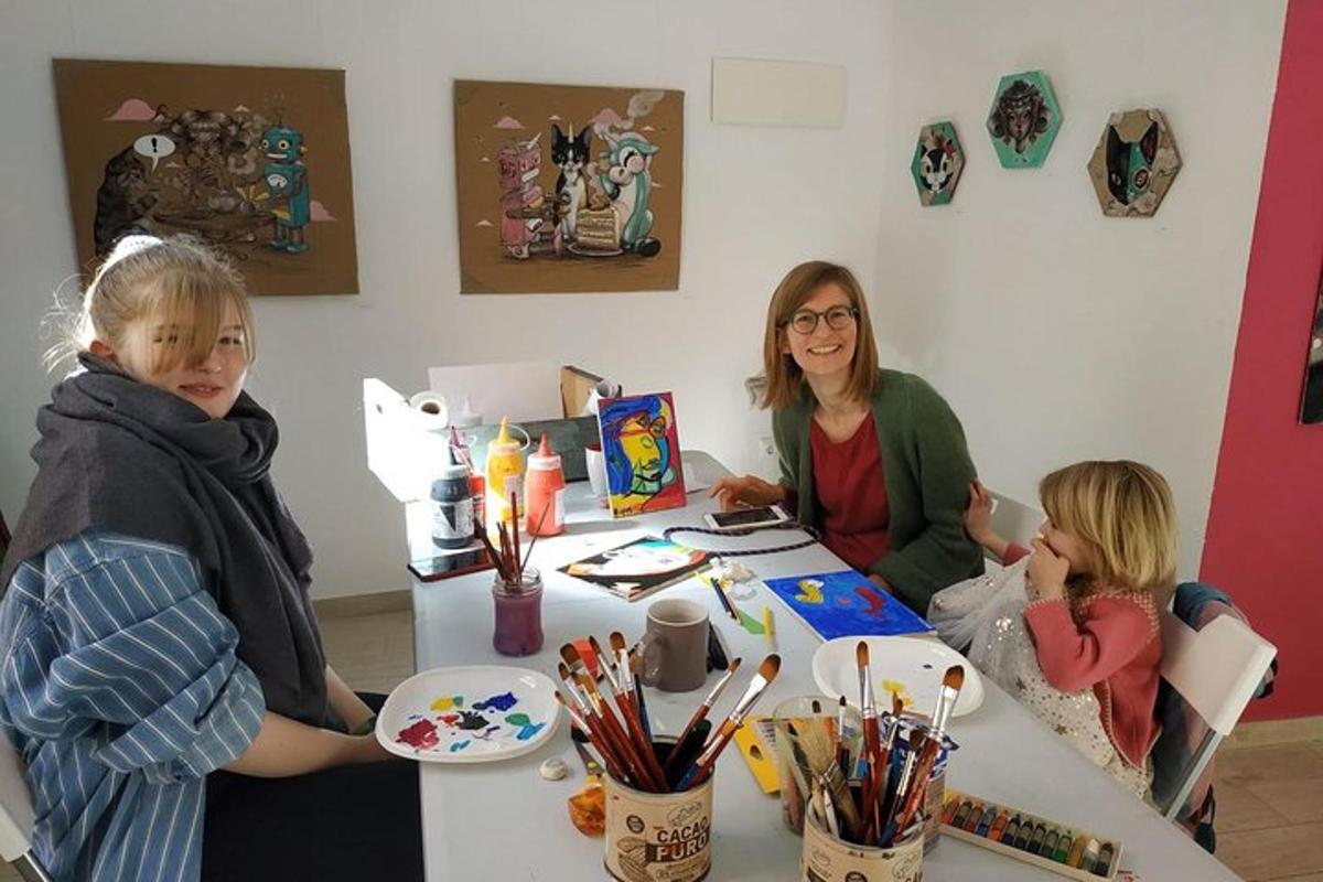 a woman and two children sitting at a table with art supplies
