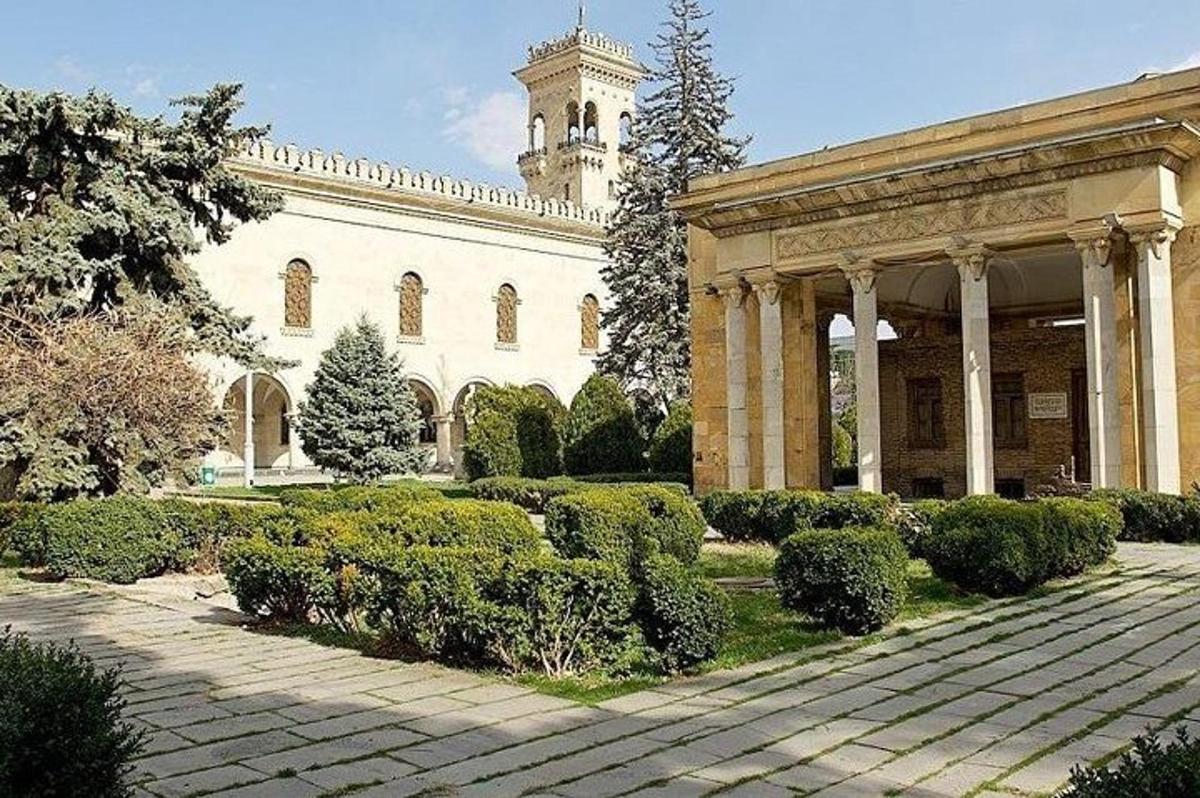 un grande edificio con una torre dell'orologio in un giardino
