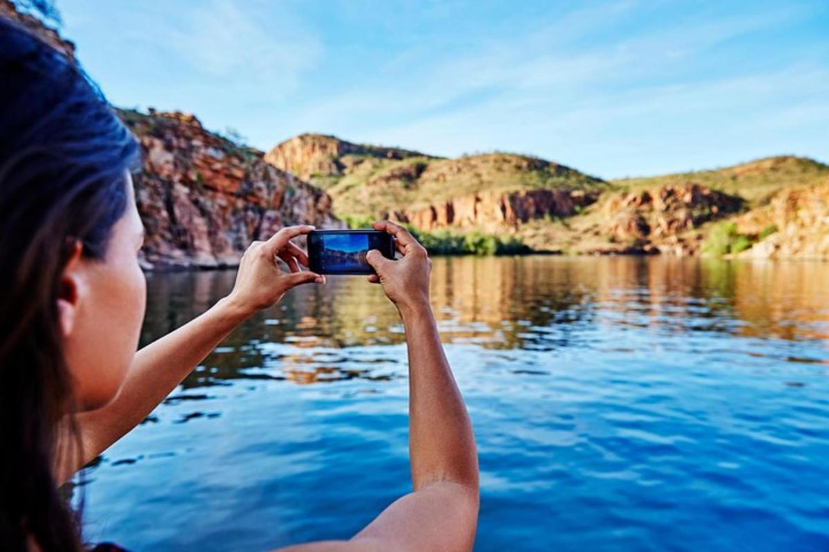 a woman taking a picture of a lake